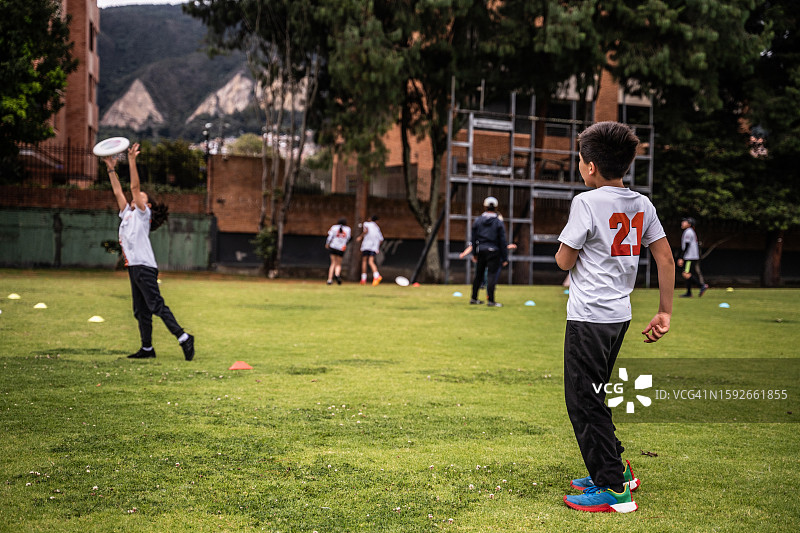 男孩在公园里和朋友们玩飞盘图片素材