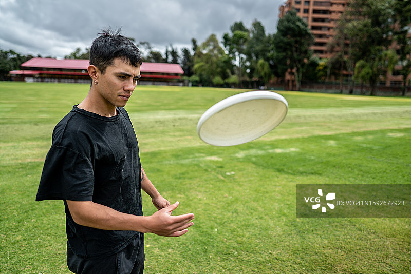 年轻人在公园里扔飞盘图片素材
