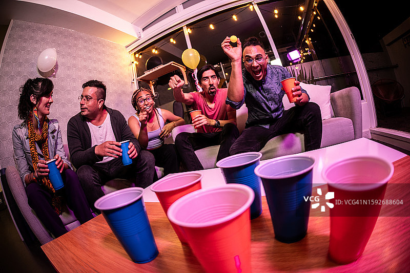 朋友们在家里的派对上玩啤酒乒乓球图片素材