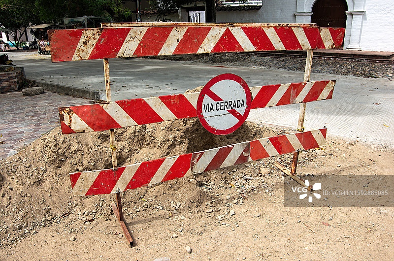 道路施工中的城镇街道，西班牙语标志牌显示“道路封闭”的路障图片素材