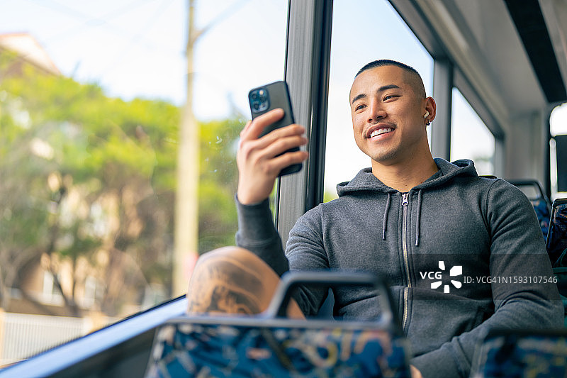 在公共汽车上使用手机的亚洲男人图片素材