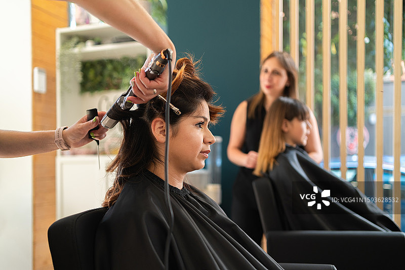 理发师使用电卷发棒为顾客做头发图片素材