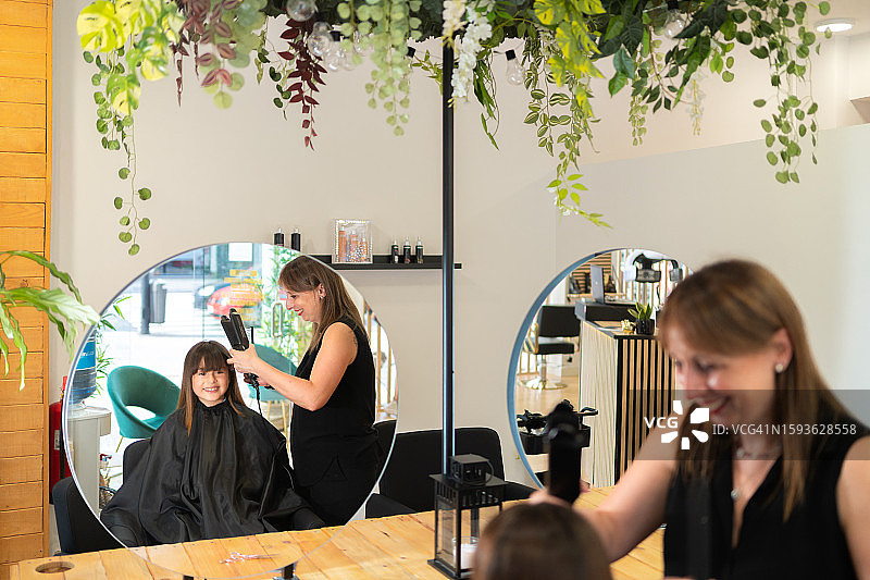 一位微笑的发型师正在拉直顾客的头发图片素材