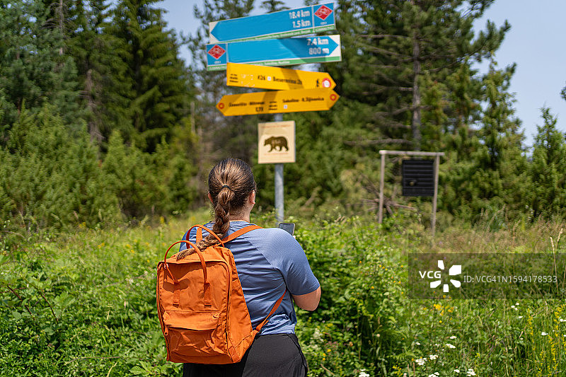 年轻女子看着森林中的路标的背影图片素材