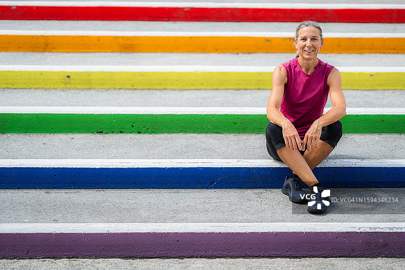 坐在户外彩虹色台阶上的运动型女人图片素材