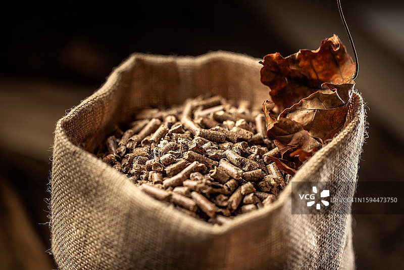 麻袋中的木制颗粒与秋叶：供暖季概念图片素材