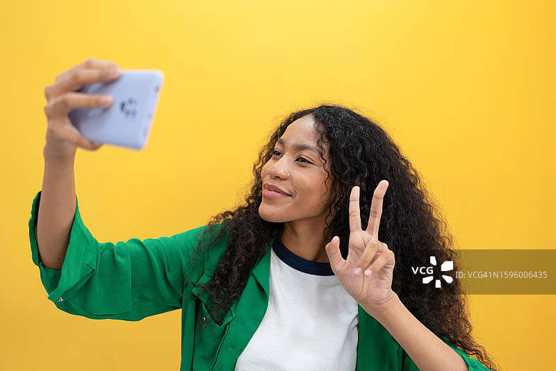 非裔美国女性散发着积极和自信的光芒。真诚的笑容反映了通过社交媒体和视频通话与亲人联系的喜悦。科技与人类情感融入日常生活。图片素材