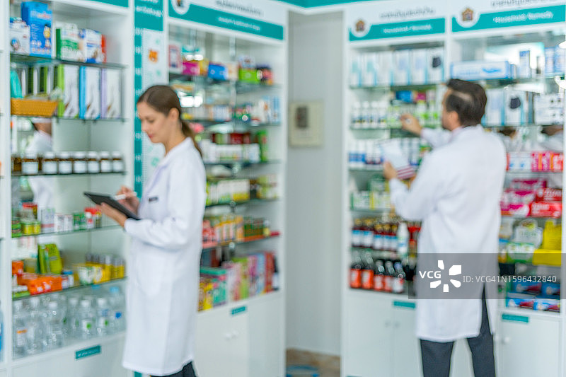 药剂师整理药房货架上的药品（背景虚化）图片素材