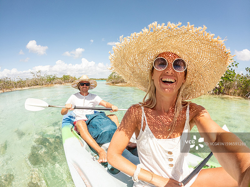 情侣在热带泻湖上划独木舟，享受国外假期自拍图片素材