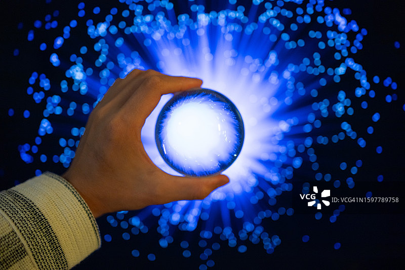 光纤背景上拿着水晶球的特写图片素材