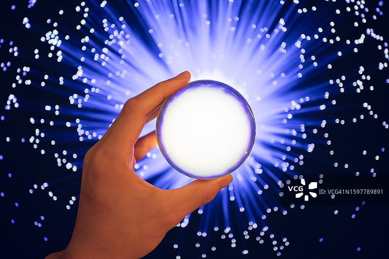 光纤背景上拿着水晶球的特写图片素材