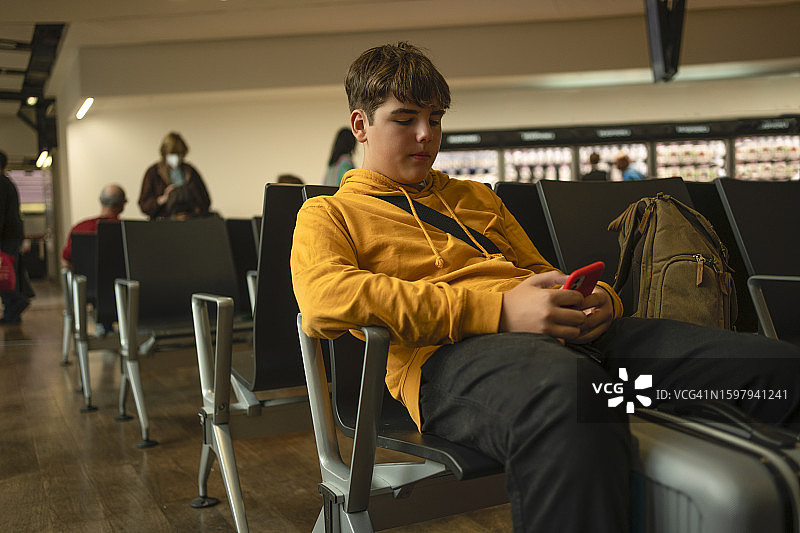 青少年在机场候机室玩手机图片素材