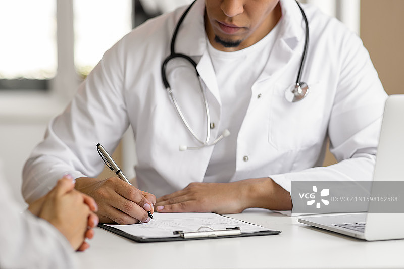 医生在诊室与患者交谈并开处方图片素材