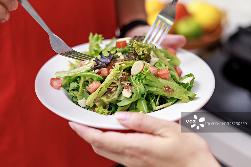 亚洲中年夫妇在锻炼后在厨房里享用健康蔬菜沙拉的特写图片素材