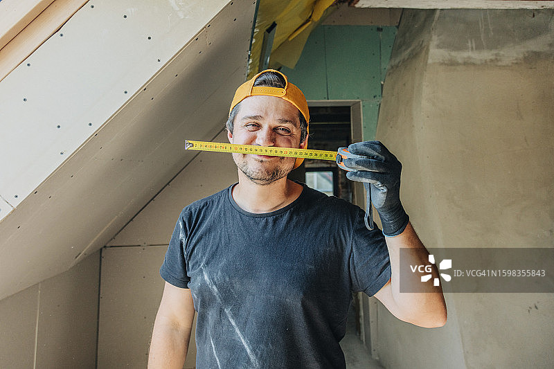 快乐的男人在阁楼里拿着卷尺图片素材