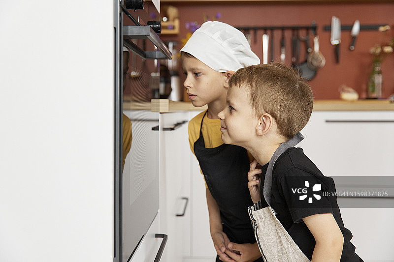 兄弟隔着玻璃看着烤箱图片素材