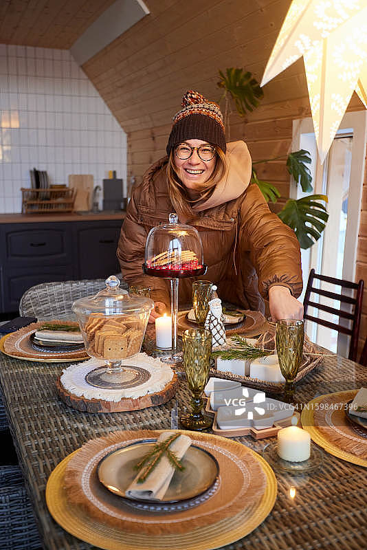 圣诞节期间，快乐的年轻女士坐在节日的餐桌旁图片素材