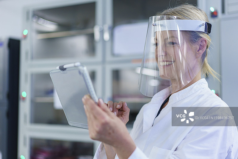 实验室里戴防护面罩微笑的中年女科学家图片素材