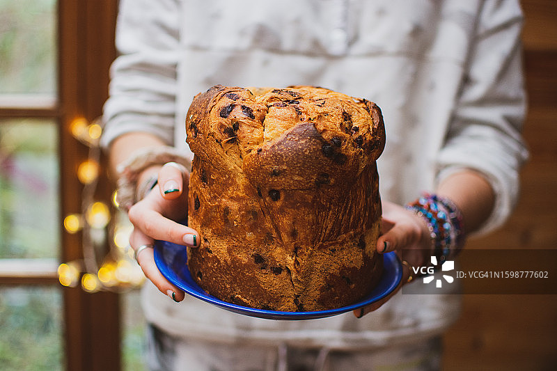 年轻女子在家中拿着装有圣诞糖果的盘子的特写图片素材