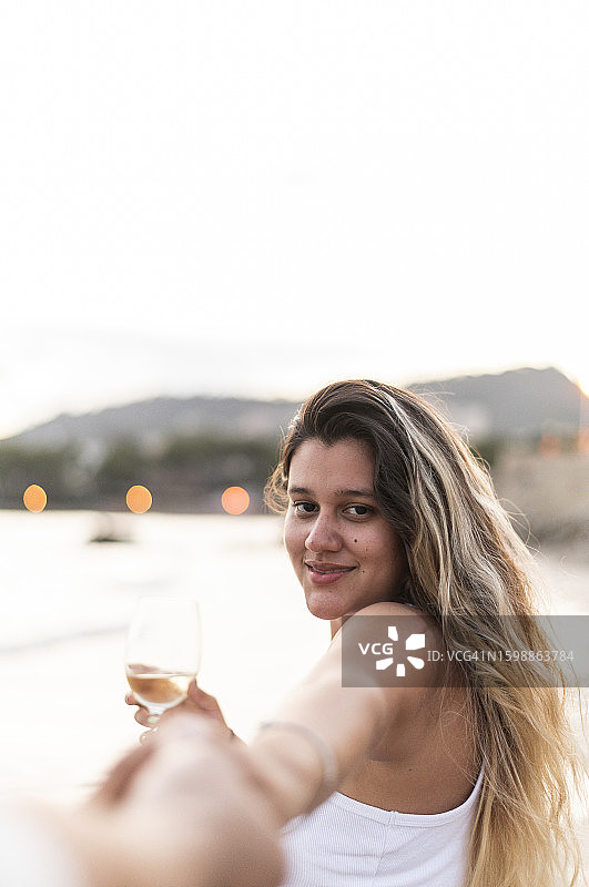 情侣在沙滩上牵手喝葡萄酒图片素材