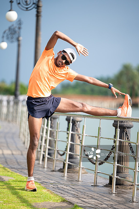 年轻男运动员在田径比赛前伸展身体图片素材