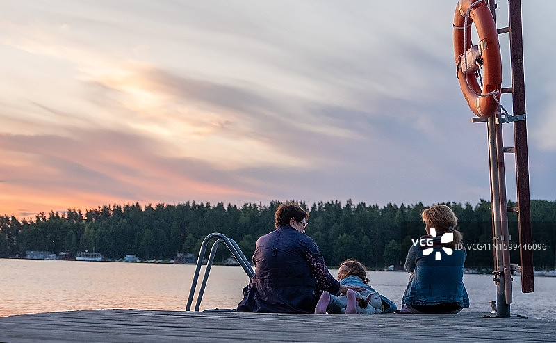 女性，年长女人，年轻女人，8岁女孩，一家白人家庭在木制码头上欣赏日落美景图片素材