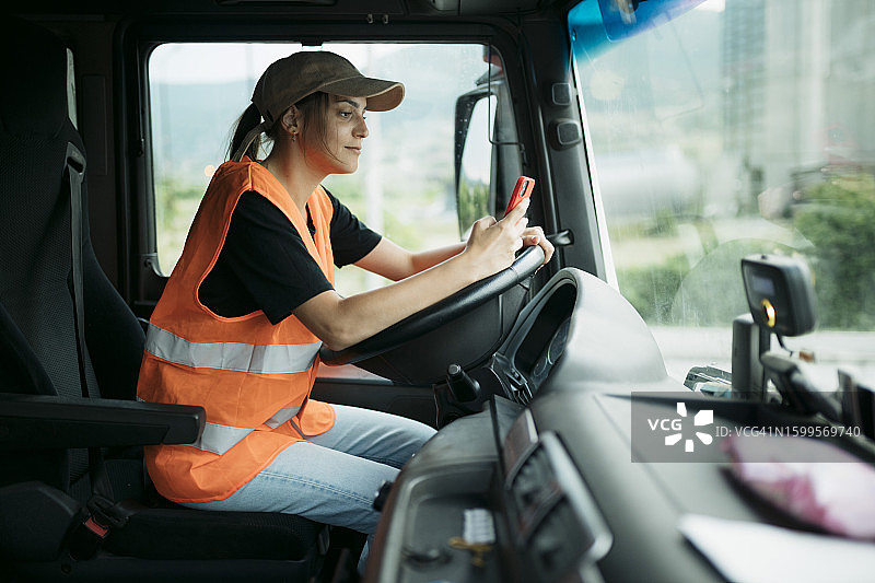 女卡车司机坐在驾驶座上发短信图片素材