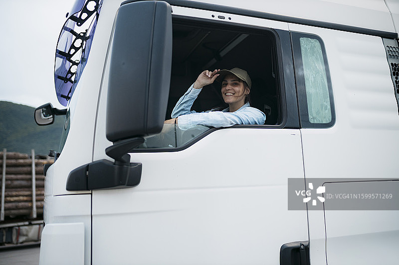 笑容灿烂的年轻女半挂卡车司机肖像图片素材
