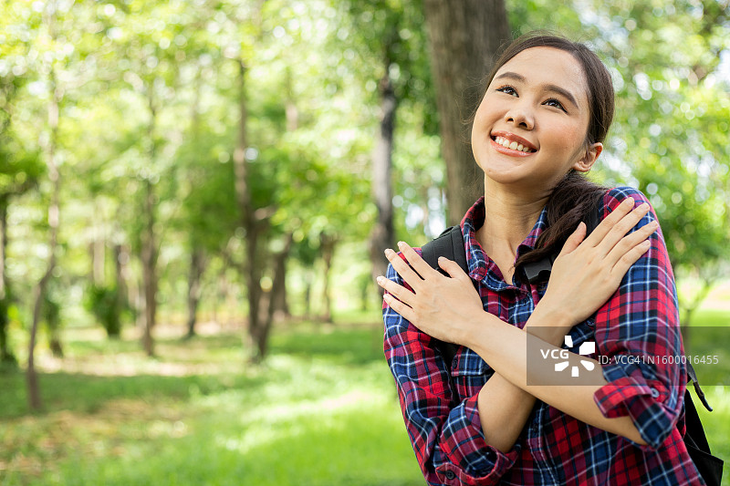 阳光明媚的日子里，女人在森林中拥抱路标图片素材