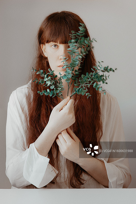 手持桉树叶的红发长发年轻女人肖像图片素材