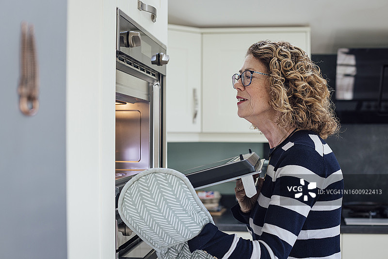 女人在烤箱里制作美味图片素材
