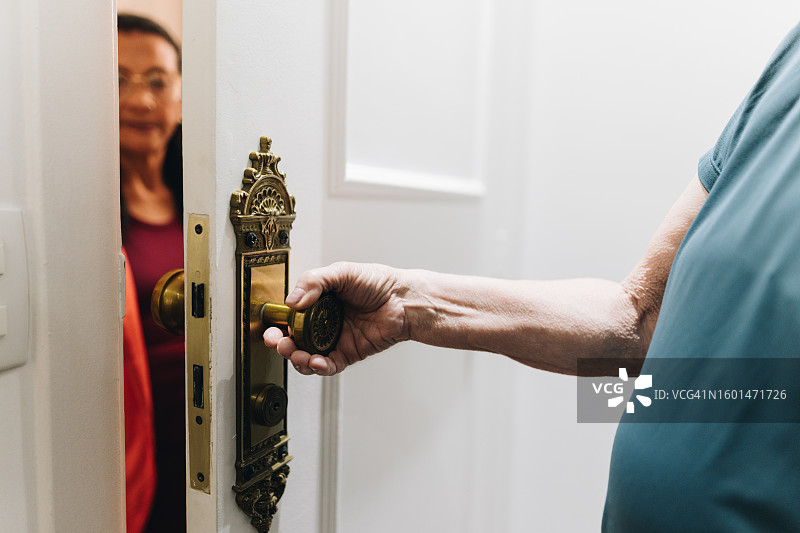 老年妇女在家为邻居开门的特写图片素材