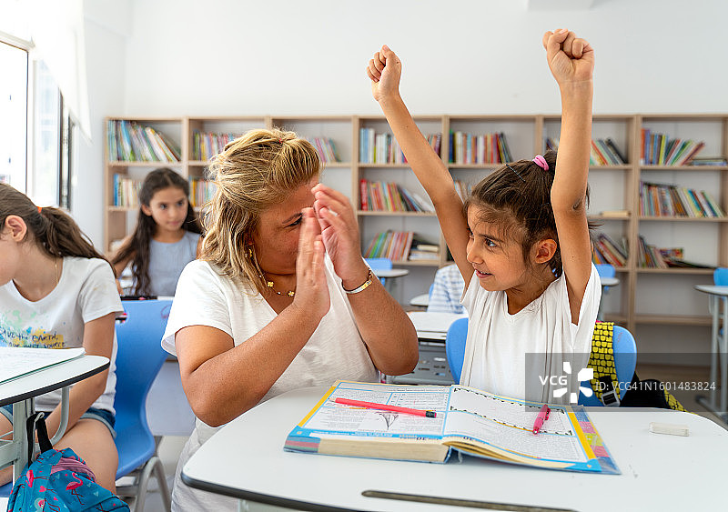 课堂上，学生举手欢庆成功，老师为他鼓掌图片素材