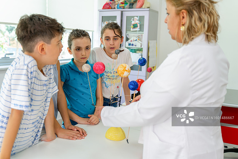 教师帮助学生在学校制作太阳系模型图片素材