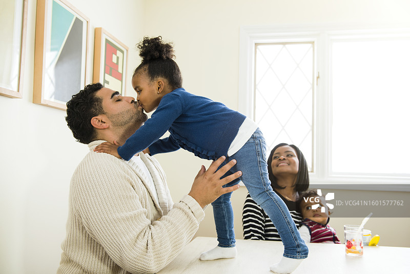 女儿在家里的桌子上亲吻父亲图片素材