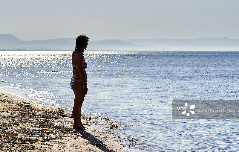 海滩夏日度假：赤脚女子在沙路上行走的阴影和剪影图片素材