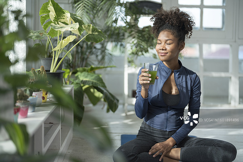 快乐的年轻女人在瑜伽锻炼后放松身心并享用健康食品图片素材