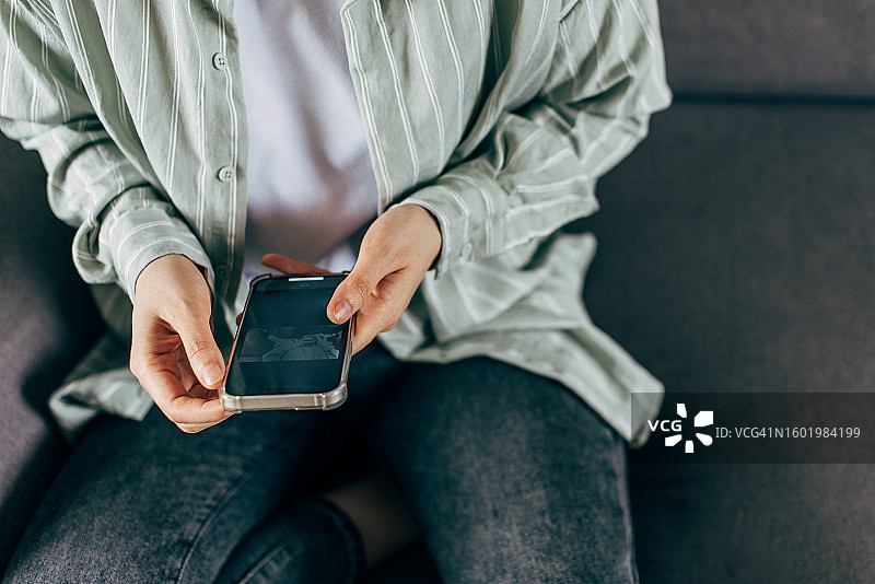 夜晚在家，女人用笔记本电脑查看智能手机特写图片素材