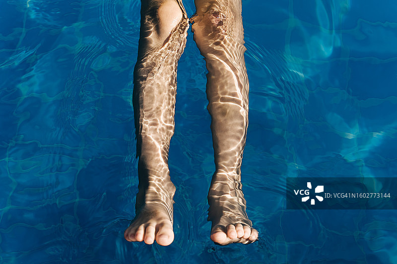 泳池中水下的孩子腿部，阳光明媚的夏日，极简主义图片素材