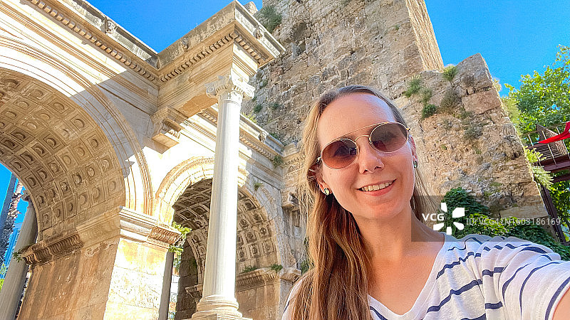 在土耳其安塔利亚老城旅行并探索著名景点哈德良拱门时自拍的女人图片素材