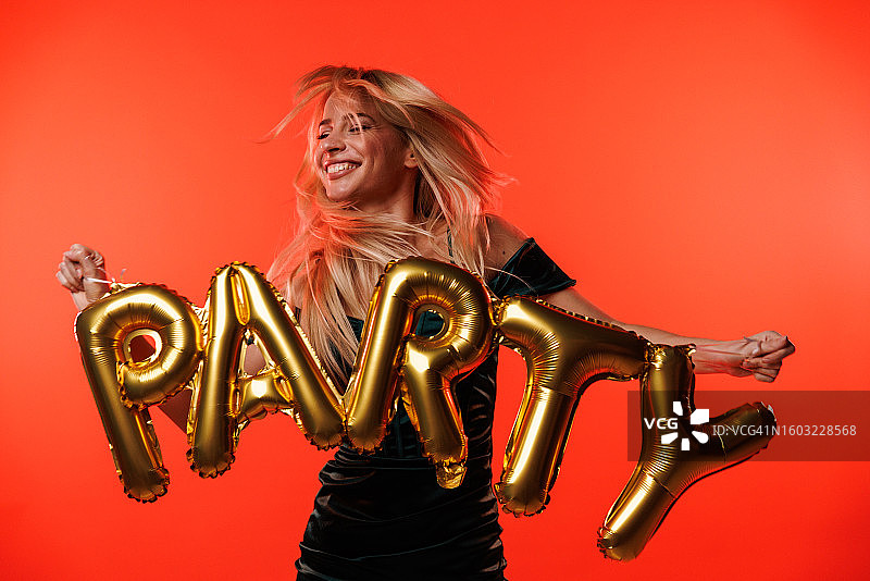 年轻金发女子拿着“派对”气球跳舞图片素材