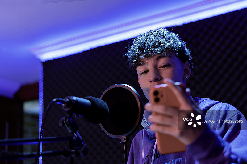 男孩在家用录音棚里用麦克风唱歌并录制音乐图片素材