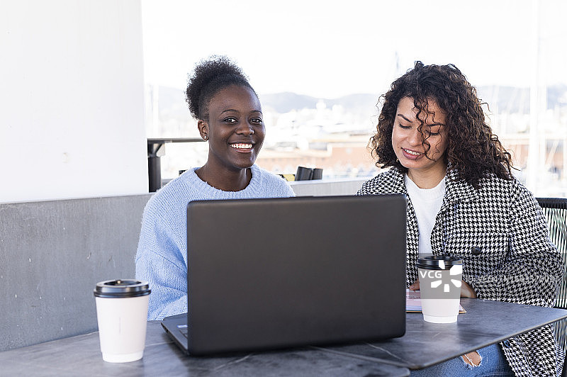在自助餐厅使用手机的两位多种族女人图片素材