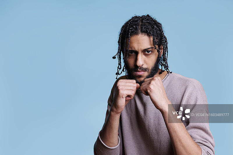 站在蓝色背景前的年轻男子肖像图片素材