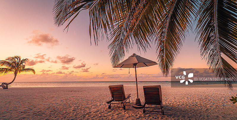 浪漫日落海滩：情侣椅、遮阳伞与宁静的蜜月之旅图片素材