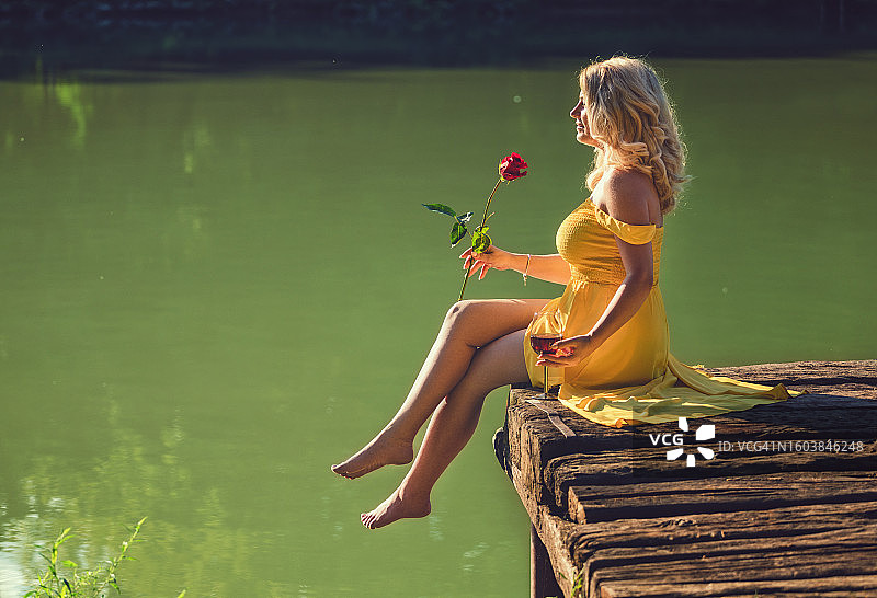 一位身穿黄色连衣裙的美丽女人在湖边享受她的时光图片素材