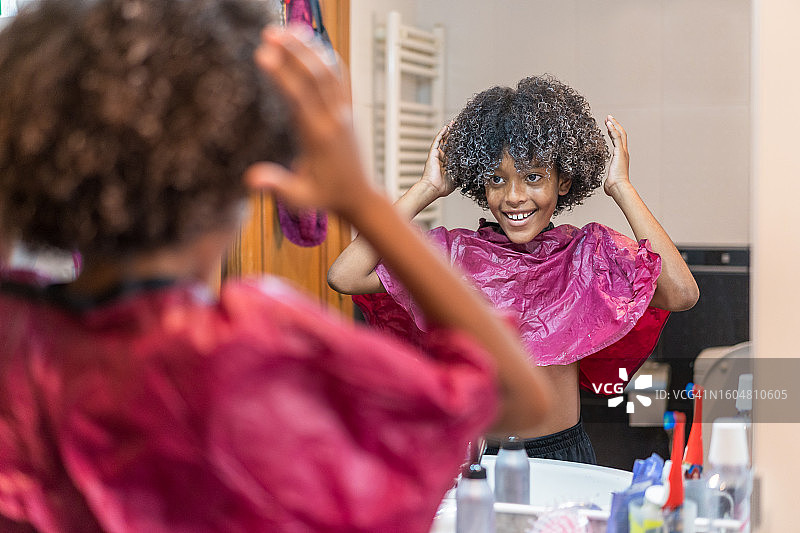 男孩对着镜子高兴地整理他染过的卷发图片素材