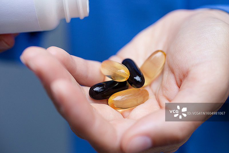 女性手持胶囊特写，保健和药丸概念图片素材