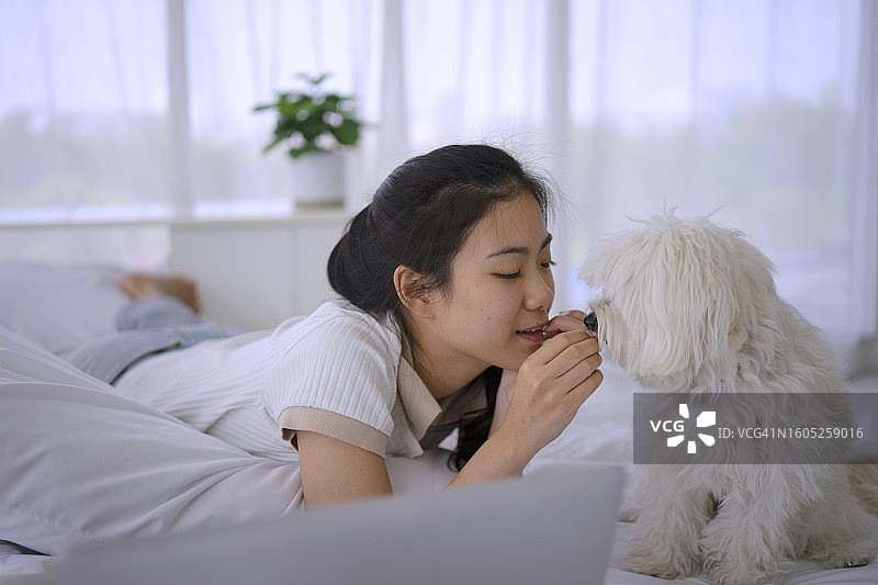 年轻女人在家和她的狗玩耍图片素材