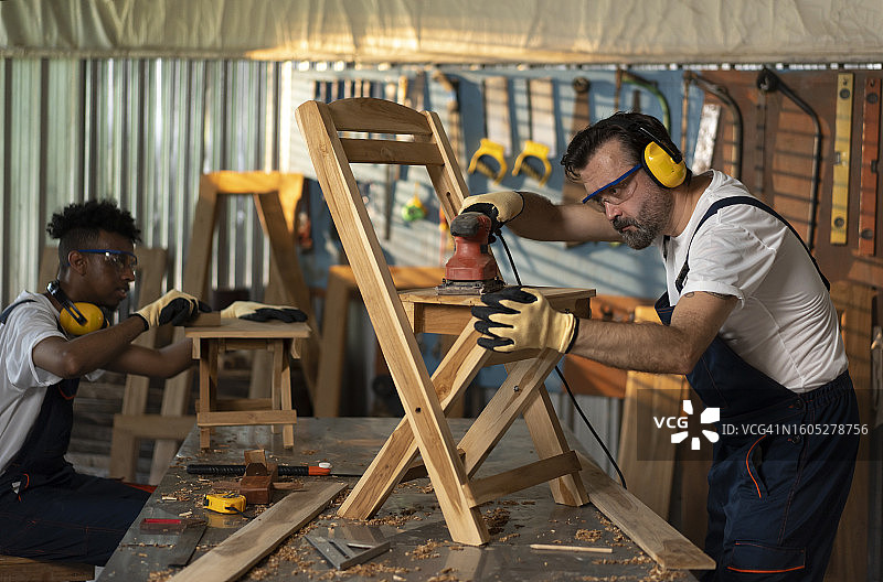 男性家具设计师正在仔细打磨椅子框架图片素材